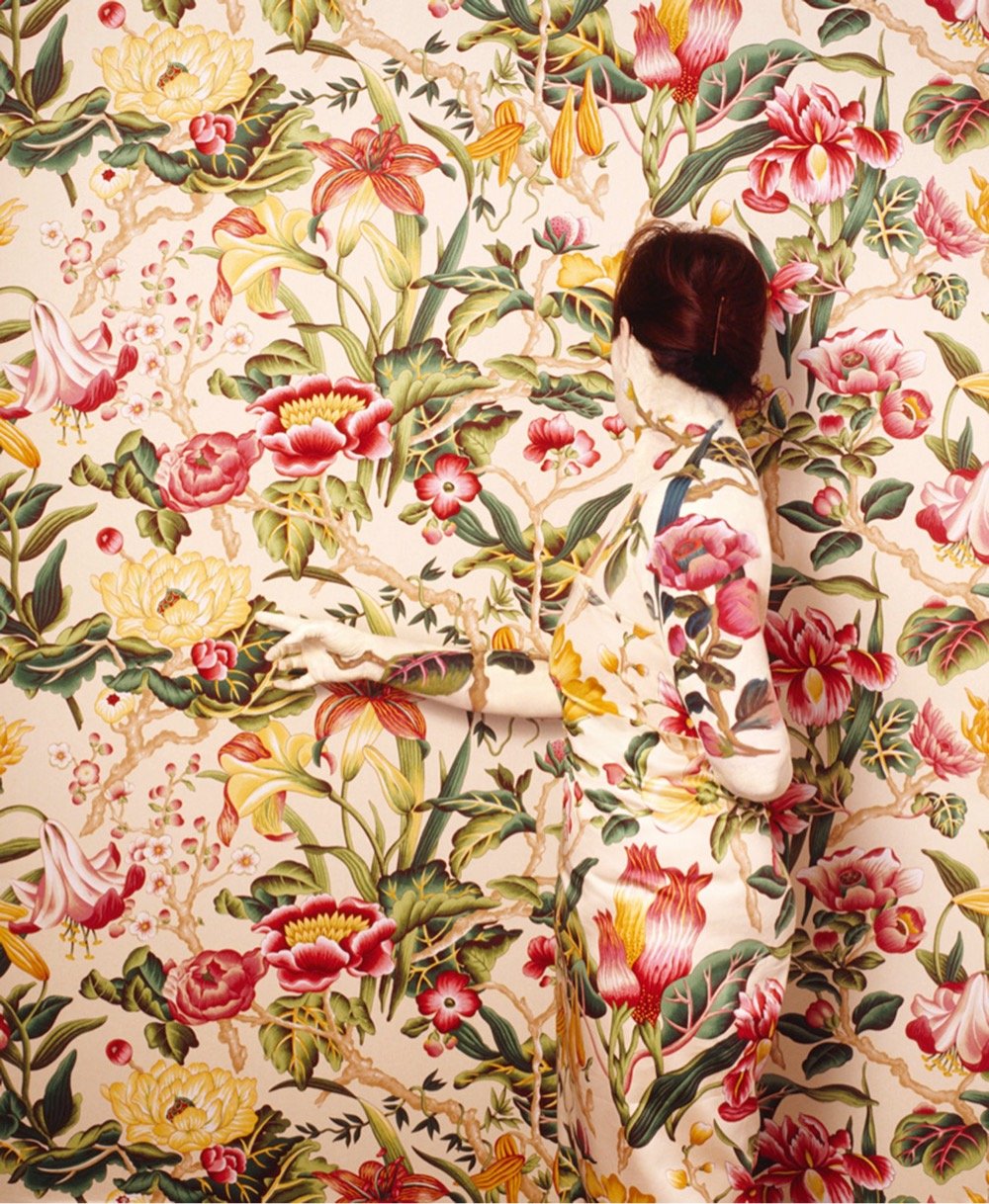 a woman camouflaged to blend into a patterned wall