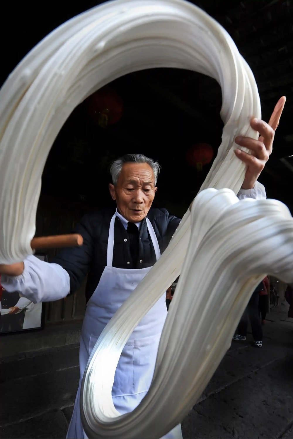 a man in a white apron pulls taffy