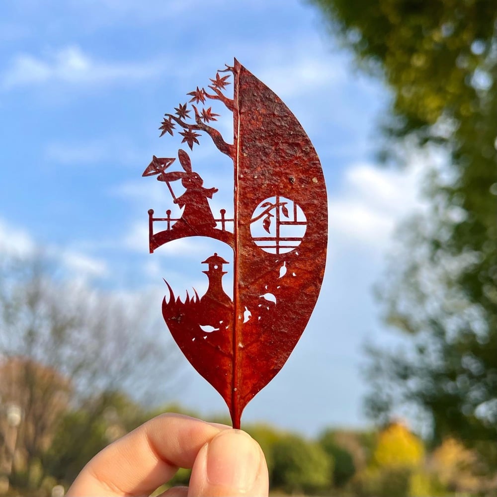 leaf cutout art of a rabbit with an umbrella