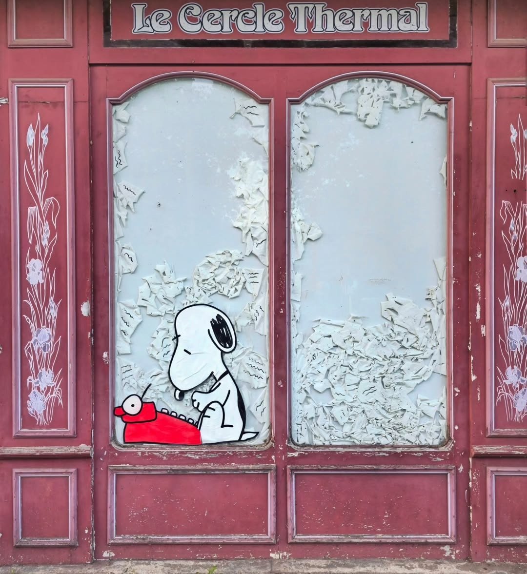 a painting in a window of Snoopy typing on a typewriter