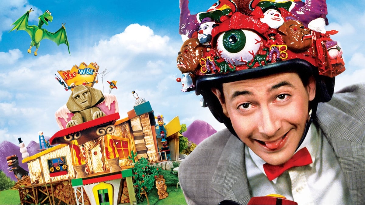 in the foreground, Pee-wee Herman wears a wacky hat with an unusual house in the background