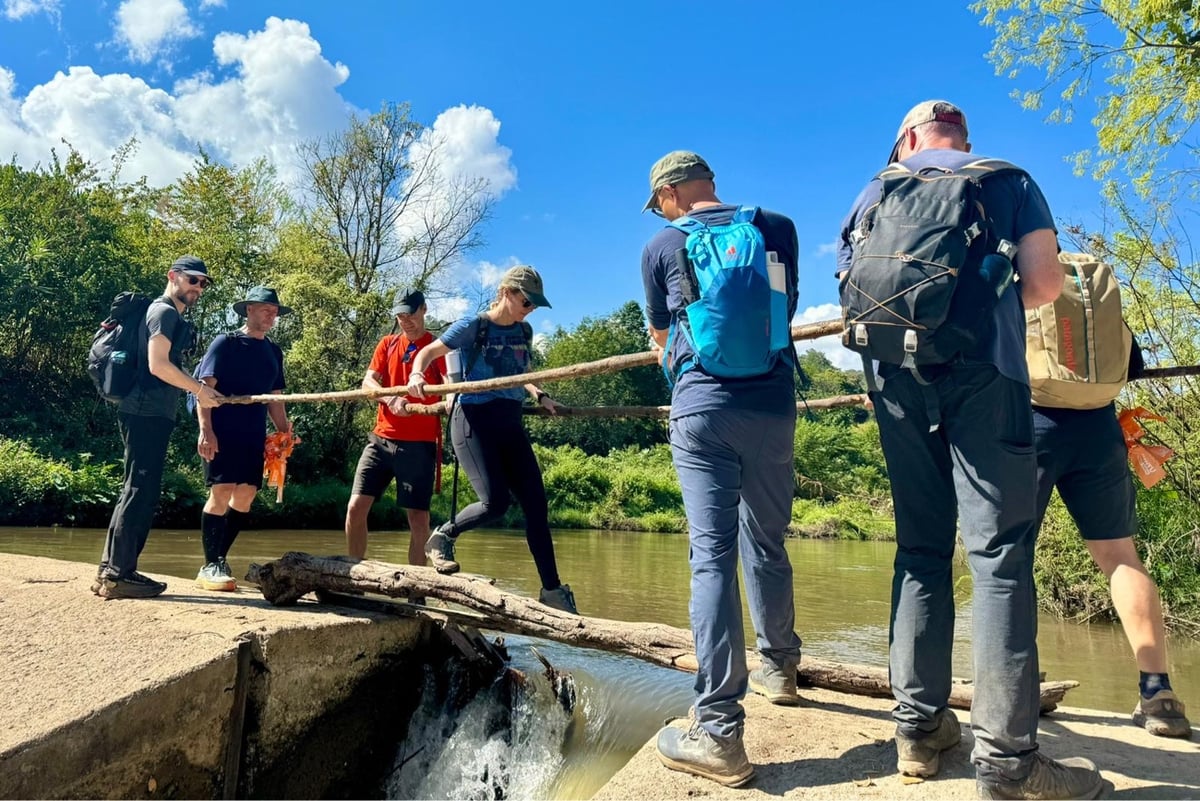 a group of people helping someone across a dam on a makeshift bridge