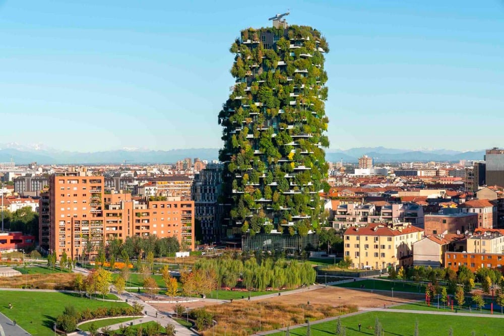 a residential building with plants and trees on every balcony