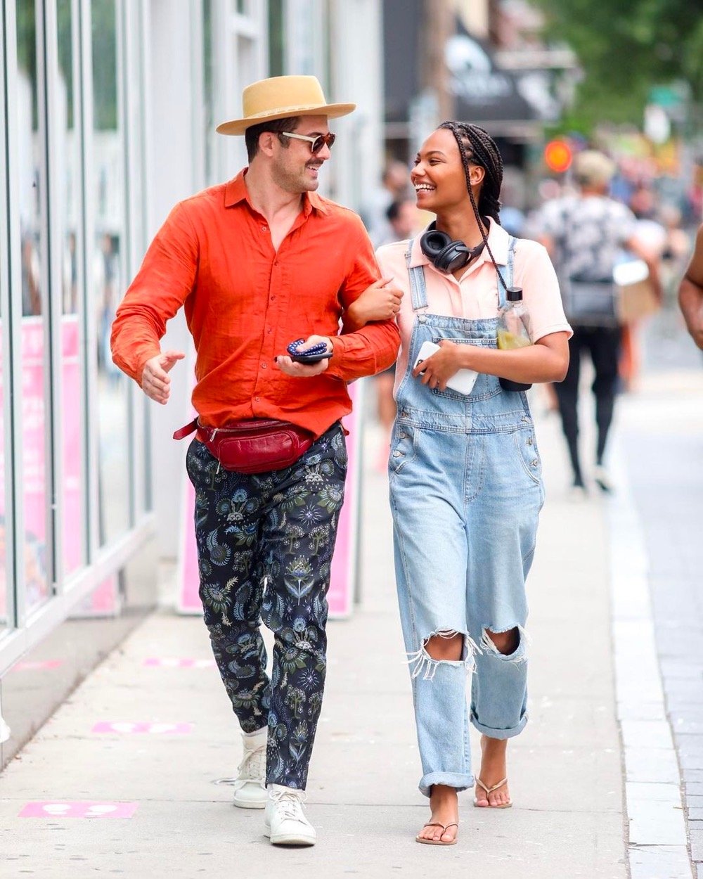 a man and a woman walk arm in arm down the street