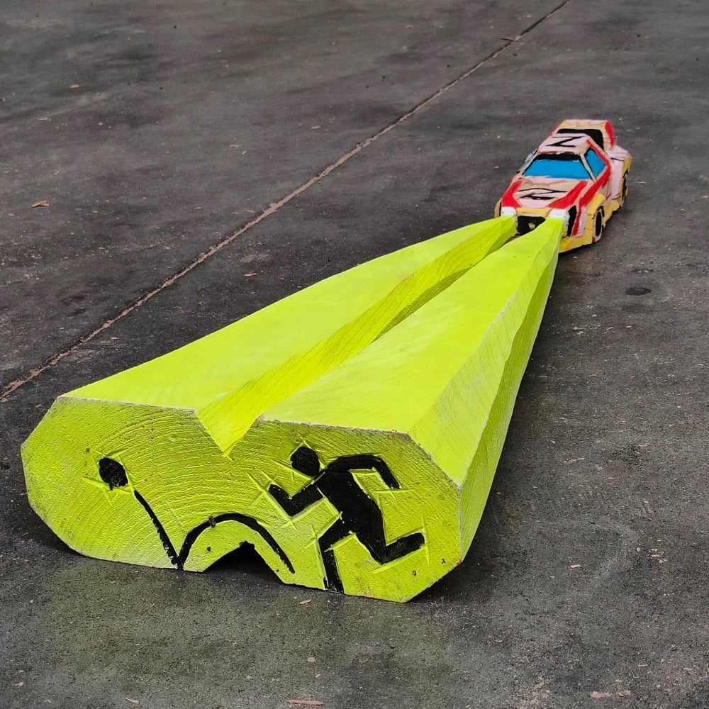 a carved wooden car with wooden headlights coming out of it with an image of a person chasing a ball in the beams