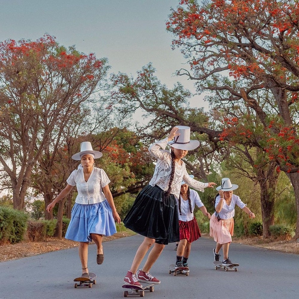 a group of Bolivian women skateboard in traditional clothing