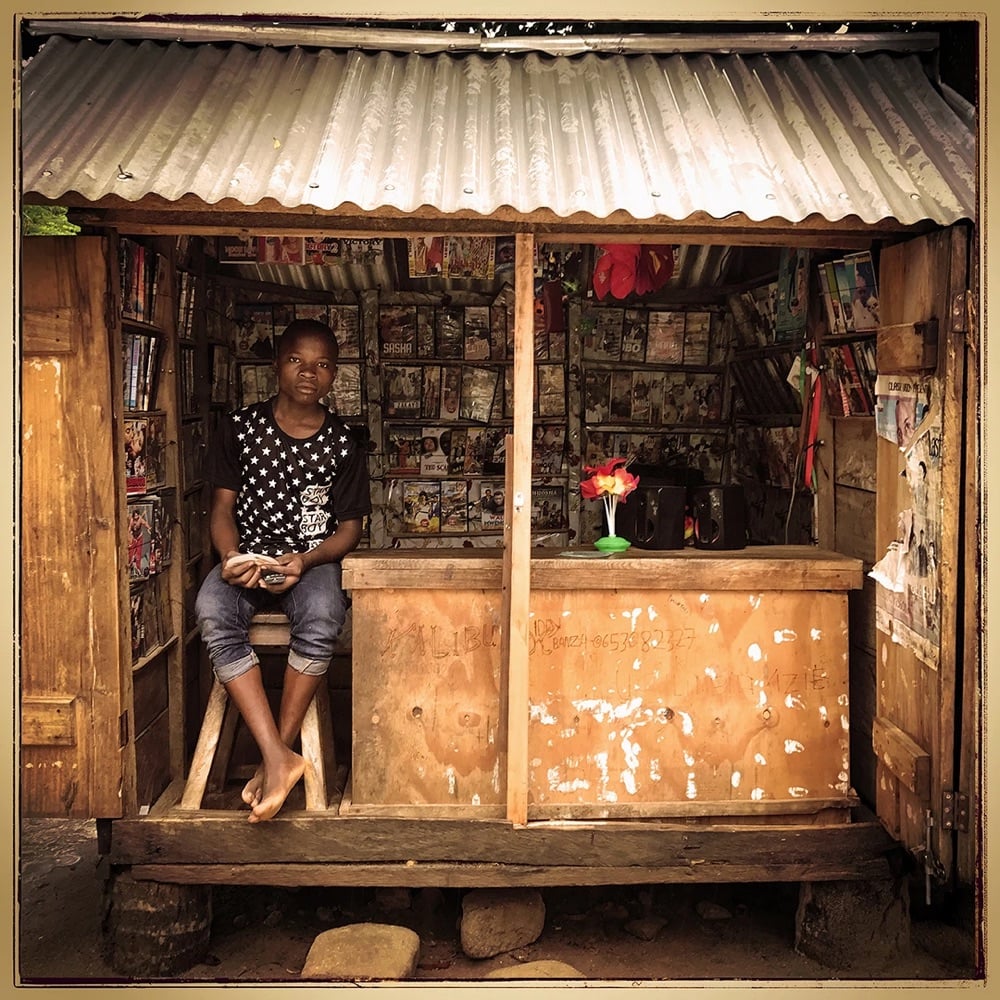 a young newsseller poses in his newsstand