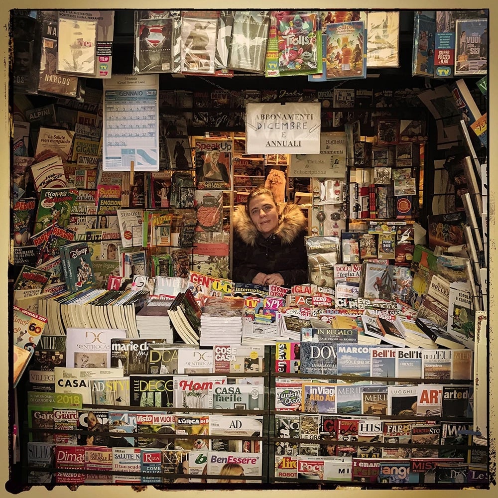 a newsseller looks out of her newsstand