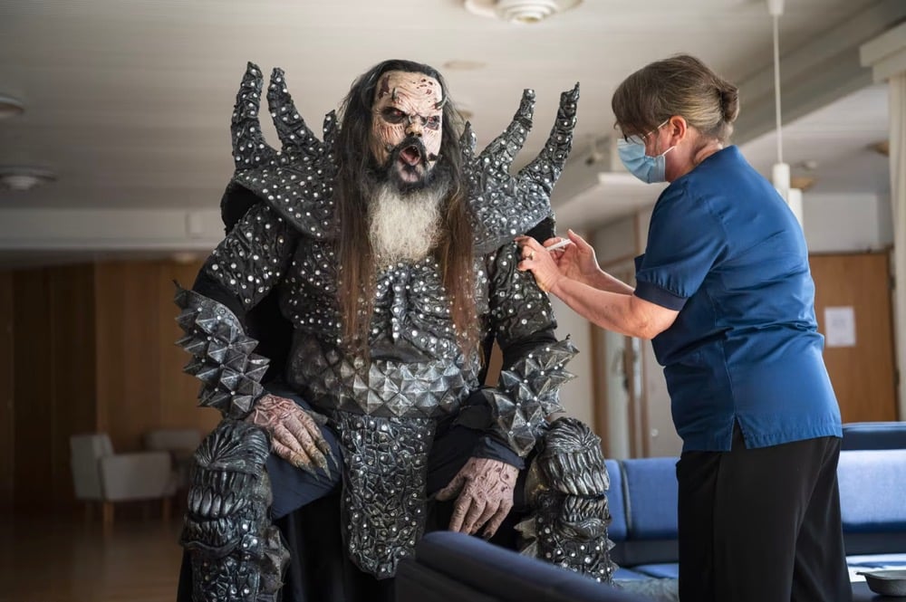 a man dressed in an elaborate costume get a vaccine shot