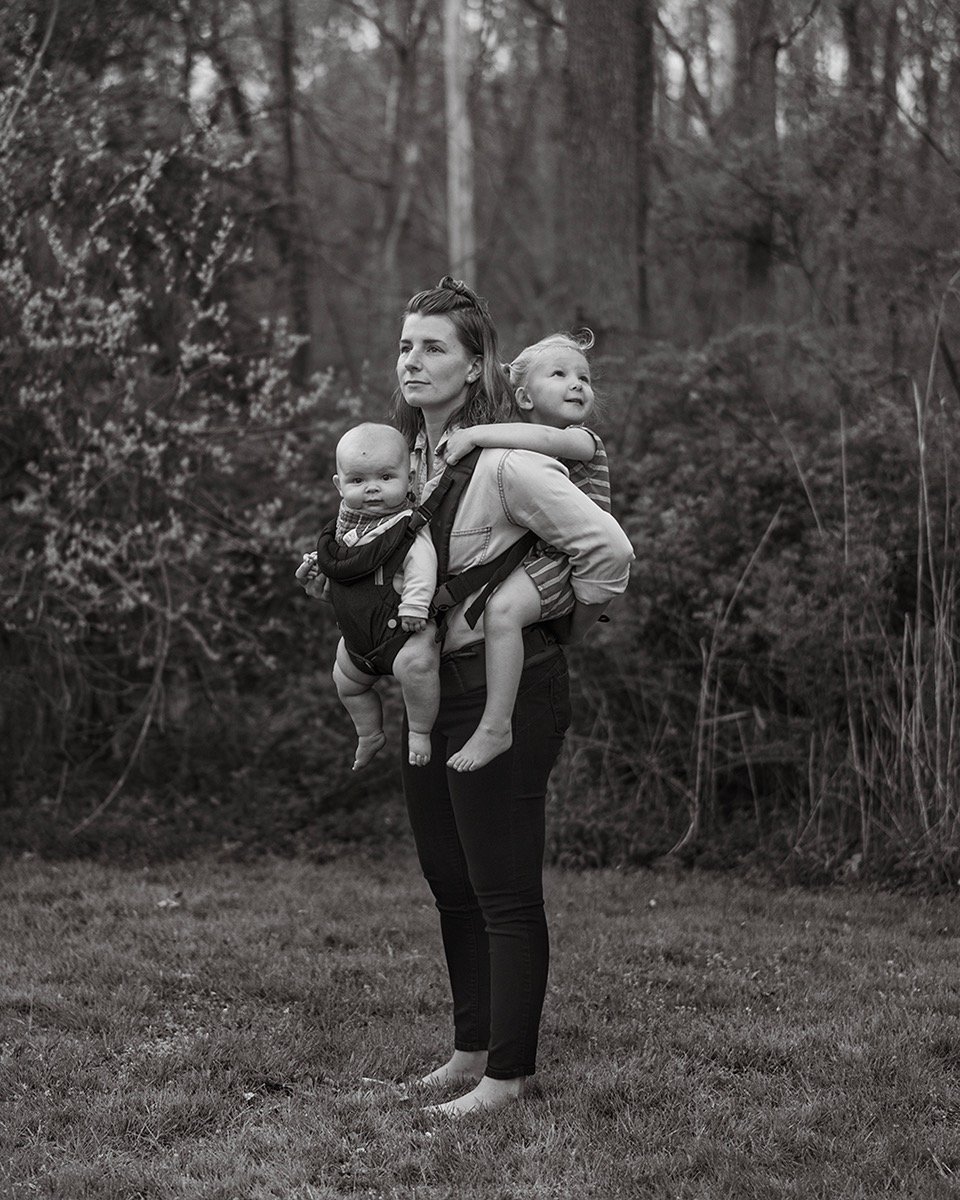 a woman carrying two children